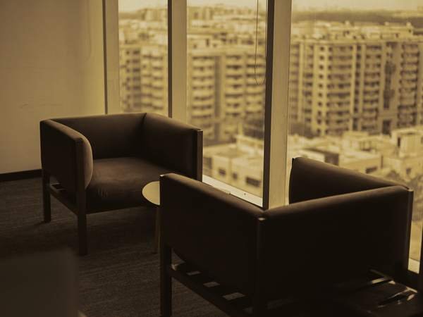 Two armchairs beside a window in warm light.